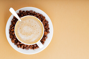 Cup of coffee on a beige background. Roasted coffee beans in a white saucer. Earth color concept....