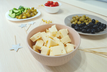 Sliced cheese close-up. The process of making canapes for the holiday. Blurred background.