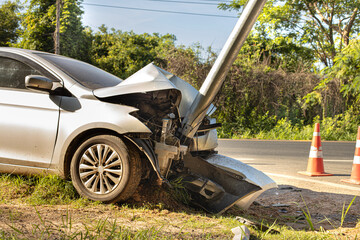 The white sedan was involved in a collision with an electric pole. - obrazy, fototapety, plakaty