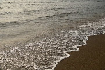 砂浜に打ち寄せる穏やかな波と白い泡