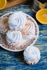 Delicious marshmallow with orange filling in a vintage plate, sliced orange on a cutting board and tea in a glass.