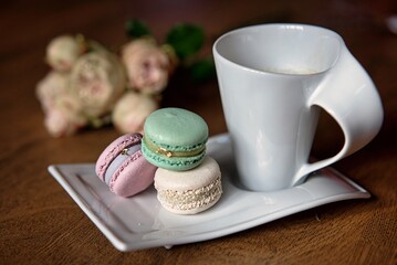 Macaron and cup of coffee on wooden background
