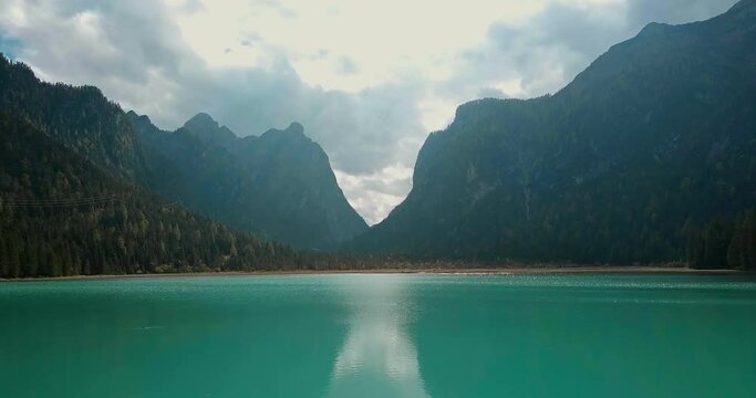 Aerial drone forward flight over lake (Lago) Dobbiaco (Toblacher) in partly cloudy weather 4k.