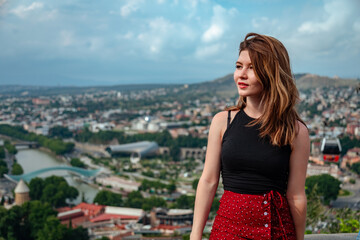 Beautiful young woman standing at Tbilisi city panorama