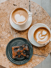 hot coffee latte art in white cup and chocolate brownie on white plate served in vintage wood tray on rustic wood table top view.