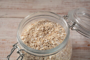 Uncooked oatmeal in  a bowl on the table. Dehusked, hulled oats, rolled into large whole flakes. Porridge oats, used in granola or muesli.