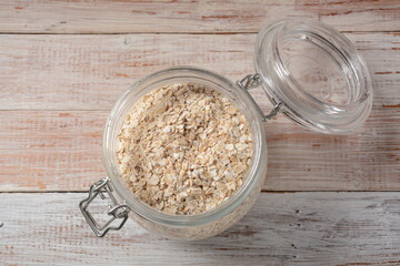 Uncooked oatmeal in  a bowl on the table. Dehusked, hulled oats, rolled into large whole flakes. Porridge oats, used in granola or muesli.