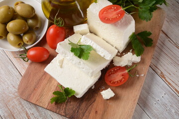 Fototapeta na wymiar Feta cheese, olives and cherry tomatoes, green herbs and olive oil. Greek snack