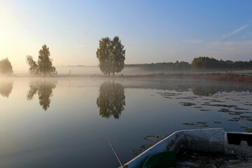 Sunrise in the morning fog on the reservoir. Beautiful autumn nature. Angler's morning. Unique image of the environment.
