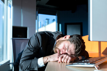 Close-up photo of a businessman, man sleeping at his desk, during the day at the computer