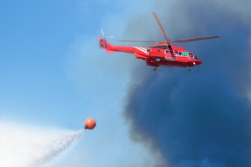 Fototapeta na wymiar Firefighter rescue helicopter with helitanker droping water