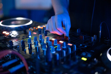 Close-Up of Dj Mixer Controller Desk in Night Club Disco Party. DJ Hands touching Buttons and Sliders Playing Electronic Music . High quality photography.