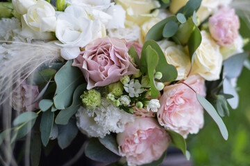Modern bridal bouquet made from roses, freesia, eustoma and eucalyptus on dark background.