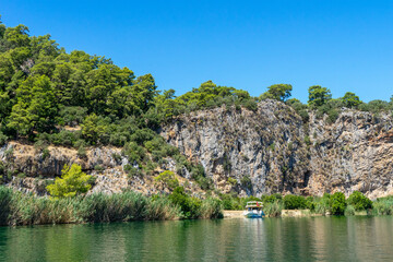 Tourist pleasure boat on the Dalyan River, next to the rocks, which contain the Lycian tombs, in Mugla Province located between the districts of Marmaris and Fethiye on the south-west coast of Turkey