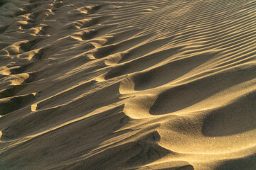 Footprints in sand dunes beautifully shaded from the sunset