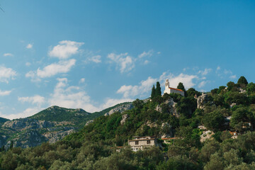 Bell tower of the church looks out from the green trees high in the mountains. Montenegro - obrazy, fototapety, plakaty