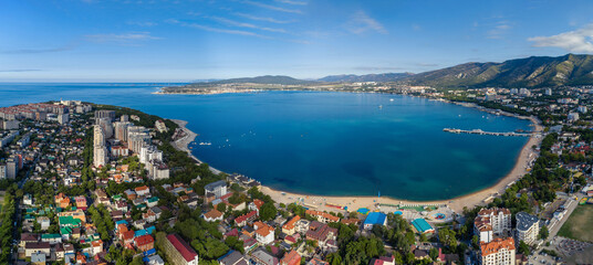 Panorama of Gelendzhik resort from a height, the Black Sea. The Gelendzhik Bay, the Caucasus Mountains are visible. Along the bay there are resort beaches, sanatoriums and boarding houses - obrazy, fototapety, plakaty