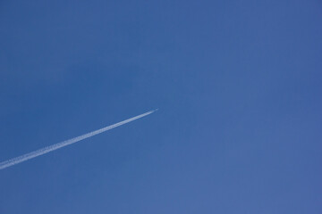 Airplane with white tail flying over blue sky in sunshine
