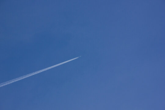 Airplane with white tail flying over blue sky in sunshine
