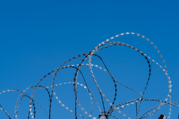Barbed wire on fence with blue sky