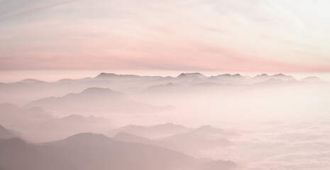 Mountain range with visible silhouettes through the morning colorful fog.