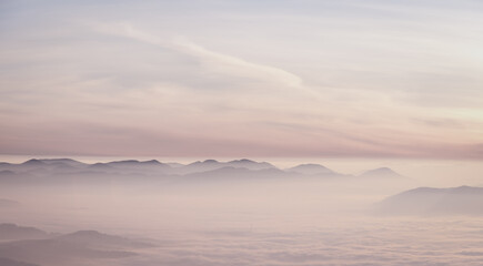 Mountain range with visible silhouettes through the morning colorful fog.
