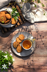 Tea Splash. Spring black tea with oatmeal cookies on a dark wooden background with flowers. Spring has come concept. First  flowers. Horizontal spring composition. Flat lay. Top view.