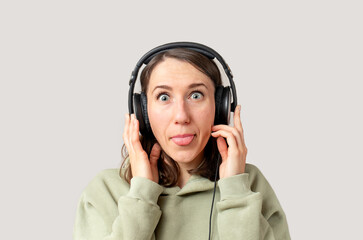 Young woman listening music with headphones and showing her tongue hit having fun fooling