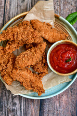 
 Crispy  deep fried   chicken strips and wedges potato. Breaded  with cornflakes chicken  breast fillets  with chilly peppers and fresh   basil on wooden rustic background