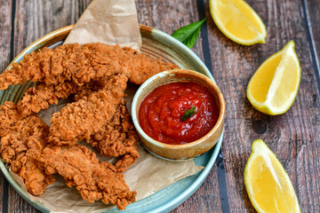 
 Crispy  deep fried   chicken strips and wedges potato. Breaded  with cornflakes chicken  breast fillets  with chilly peppers and fresh   basil on wooden rustic background