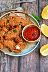 
 Crispy  deep fried   chicken strips and wedges potato. Breaded  with cornflakes chicken  breast fillets  with chilly peppers and fresh   basil on wooden rustic background