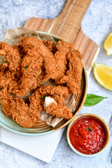 
 Crispy  deep fried   chicken strips and wedges potato. Breaded  with cornflakes chicken  breast fillets  with chilly peppers and fresh   basil on wooden rustic background