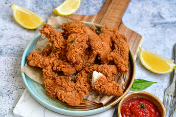 
 Crispy  deep fried   chicken strips and wedges potato. Breaded  with cornflakes chicken  breast fillets  with chilly peppers and fresh   basil on wooden rustic background