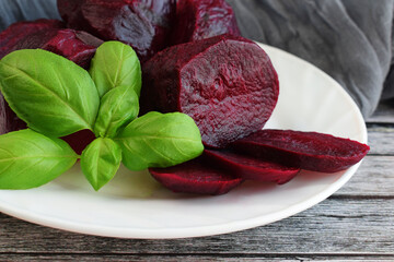 Juicy healthy beets and a sprig of basil on a white plate.