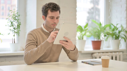 Man using Tablet while Sitting in Office