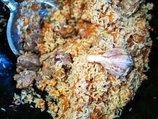 Obraz na płótnie Canvas National Uzbek dish pilaf, pilaw, plov. Rice, onion, carrot, garlic and meat in a cauldron.