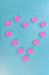 Candle Heart from pink candle. Candeles on green background. Simple composition.