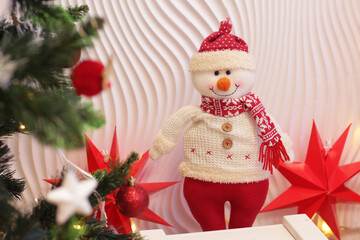 Christmas decorated room fragment with xmas tree and snowman, red stars on white wall background closeup photo
