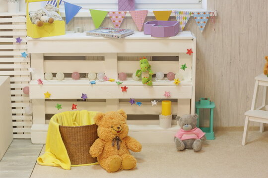 kids playroom with teddy bear, toys carpet, book and white furniture close up photo