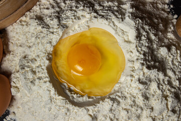 Raw egg in flour on a black background. Dough preparation. homemade baking