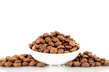 Several fragrant freshly roasted coffee beans with a white ceramic saucer, close-up, isolated on white.
