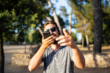 Man with sunglasses gesturing while using the mobile outdoors