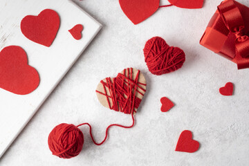 Making handmade valentine from yarn, a red heart for Valentine's Day.