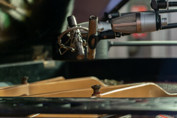 A piano with an open lid. Recording piano playing on a microphone in a recording studio. Large studio microphones.