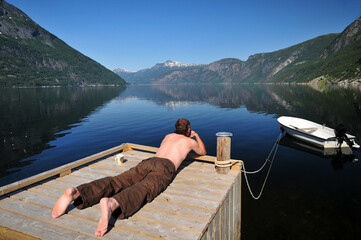 Mann liegt auf einem Bootssteg am Hardangerfjord 