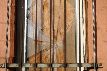Altes kaputtes eingeschlagenes Glasscheibe eines Fensters hinter Stahlgitter im Winter