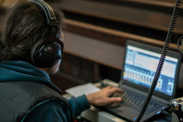 A sound engineer with headphones sits in front of a laptop while recording or listening. Male sound engineer in a recording studio