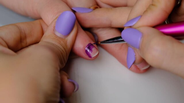 Manicurist paints nails with violet gel polish. Self made manicure service. 