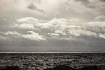 Sonne durchbricht Wolken am Meer in schwarz-wei&szlig;