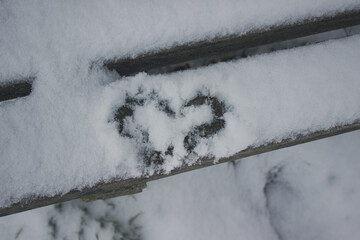 Herz im Schnee auf einer Holzbank